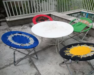چهار صندلی بانجی رنگی که در دور یک میز سفید گرد قرار دارند